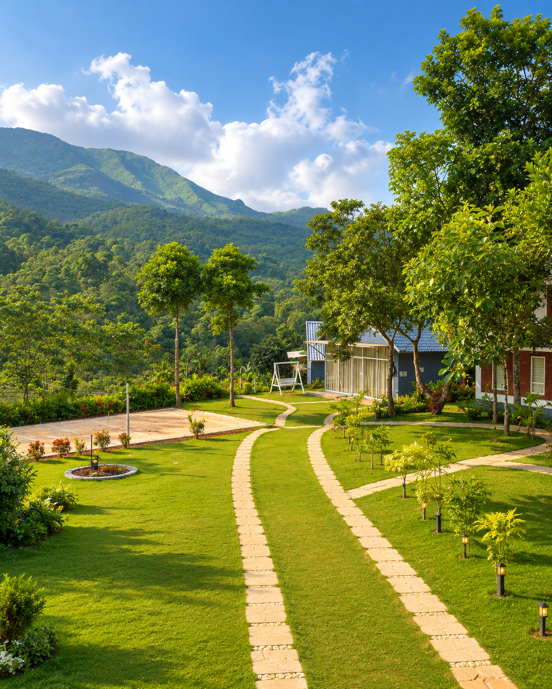 A stone garden path winding up to the villas with the Wayanad mountains behind